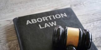 A gavel resting on a book titled 'Abortion Law'