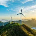 Wind turbines on a green hillside during sunset