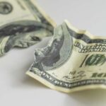 Torn and crumpled hundred dollar bills on a white surface