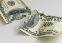 Torn and crumpled hundred dollar bills on a white surface