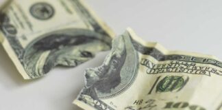 Torn and crumpled hundred dollar bills on a white surface