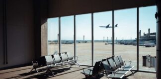 View of an airport waiting area with an airplane taking off in the background