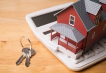 A miniature red house on a calculator with keys nearby
