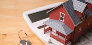 A miniature red house on a calculator with keys nearby