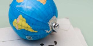 A small globe resting on a newspaper with the word 'crisis'