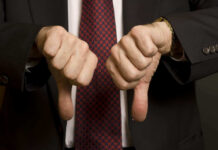 Two hands showing thumbs down in a suit.