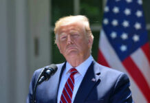 Donald Trump speaking with US flag in the back.