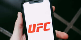 A hand holding a smartphone displaying the UFC logo