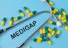 A stethoscope placed on a blue background with green and yellow capsules and the word 'Medigap'