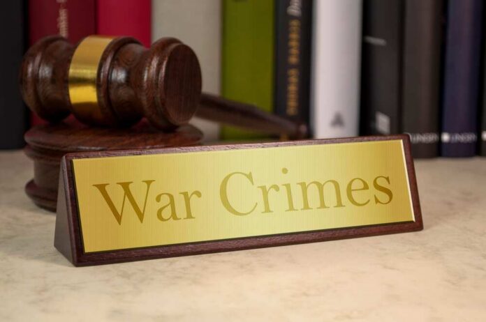 A wooden gavel next to a nameplate reading 'War Crimes'
