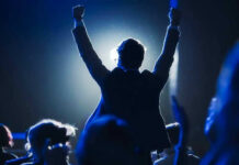 Experts PANNED It — Then This Happened! Silhouetted person with raised fists at a lit event.