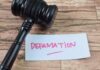 A gavel resting next to a note that reads 'DEFAMATION'