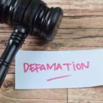 A gavel resting next to a note that reads 'DEFAMATION'