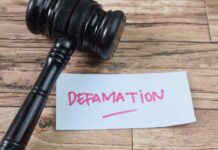 A gavel resting next to a note that reads 'DEFAMATION'
