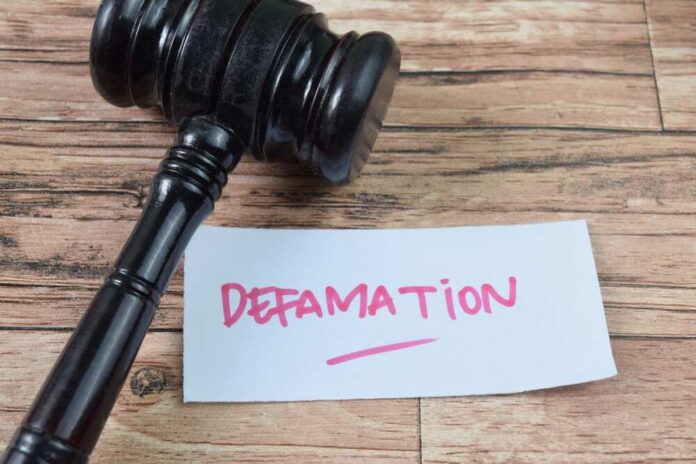 A gavel resting next to a note that reads 'DEFAMATION'