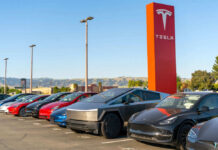 Tesla cars parked outside dealership with sign nearby