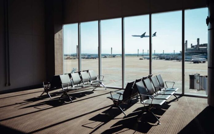 View of an airport waiting area with an airplane taking off in the background