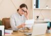 Woman in a home office reading a document with a focused expression
