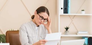 Woman in a home office reading a document with a focused expression