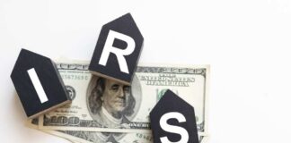Blocks spelling 'IRS' placed on top of hundred dollar bills featuring Benjamin Franklin