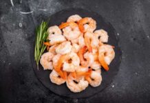 A plate of cooked shrimp garnished with green herbs
