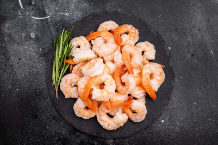 A plate of cooked shrimp garnished with green herbs