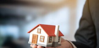 A person holding a small model house in a business setting