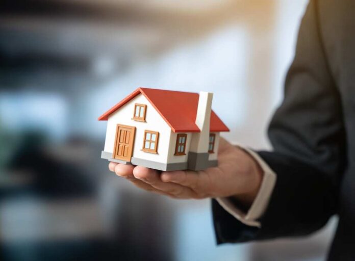 A person holding a small model house in a business setting