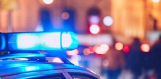 Close-up of a police car with blue emergency lights in a city at night