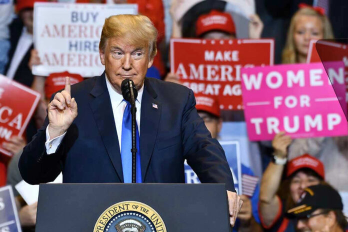 Man speaking at podium with various political signs behind.
