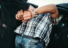 Person in handcuffs arrested by police officer.