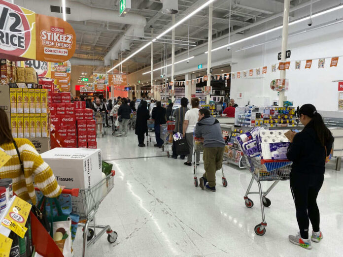 shutterstock_1665087292 Customers waiting in line at a supermarket checkout.