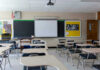 Empty classroom with desks, projector, and chalkboard.