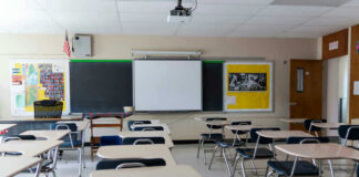 Empty classroom with desks, projector, and chalkboard.