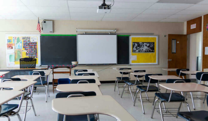 Empty classroom with desks, projector, and chalkboard.