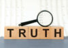 Wooden blocks spelling truth with magnifying glass