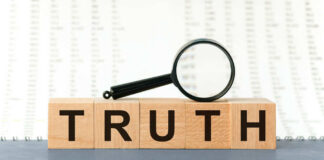 Wooden blocks spelling truth with magnifying glass