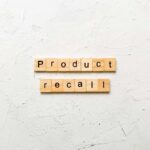 Wooden letter tiles spelling 'Product recall' on a textured surface