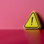 Yellow triangular warning sign on a pink background