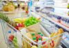A shopping cart filled with fresh fruits, vegetables, and groceries