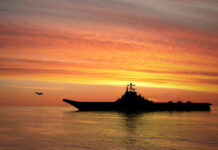 Boat War Escalates — Proof Still Missing? Silhouette of an aircraft carrier at sunset.