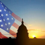 Capitol building silhouette with American flag at sunrise.