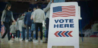 People in line next to Vote Here sign