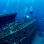 Divers exploring a sunken shipwreck underwater