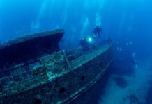 Divers exploring a sunken shipwreck underwater