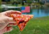 Pepperoni pizza slice on a paper plate over an American flag
