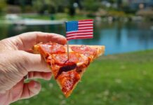 Pepperoni pizza slice on a paper plate over an American flag