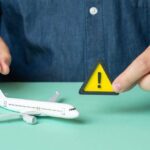 A person holding a warning sign next to a model airplane