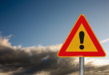 Search Grid Expands — Answers Don’t A triangular warning sign with an exclamation mark against a cloudy sky