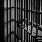 Black and white prison cell bars in dim light.